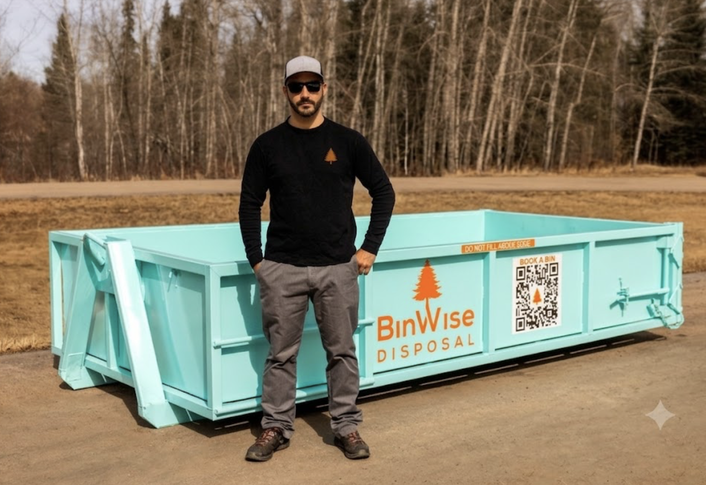 Man stands beside a large turquoise dumpster labeled "BinWise Disposal" with a QR code. He's wearing sunglasses and a black shirt with an orange